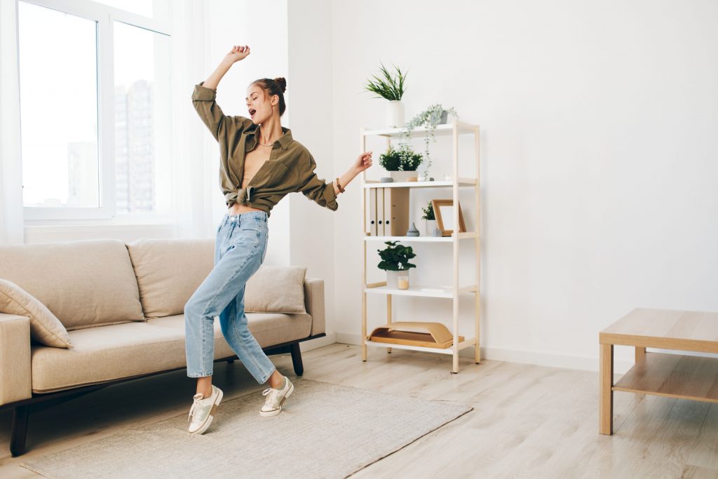 Jumping for Joy: A Happy Woman Dancing Carefree in her Home, Enjoying Music and Fun on the Sofa